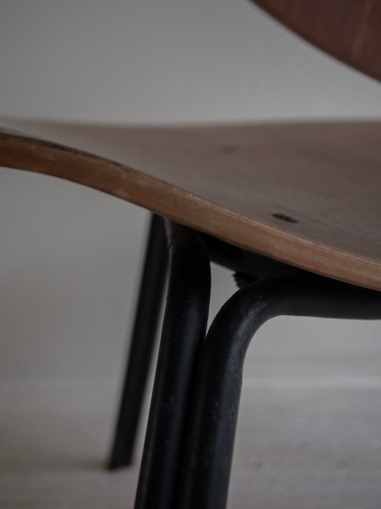 Side view of a Bicci de' Medici Osvaldo Borsani - P31 Mid-Century chair featuring a wooden seat and black metal legs. The spotlight is on the textured connection, set against a soft, blurred background that echoes Borsani's elegant designs.