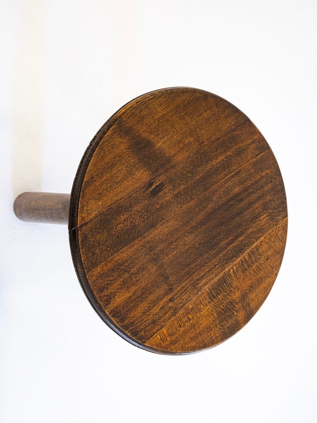 A top-down view of a 1940s Charles Dudouyt table and chair set by antibeige highlights its smooth, polished oak surface against a plain white wall, emphasizing the simplicity and craftsmanship.