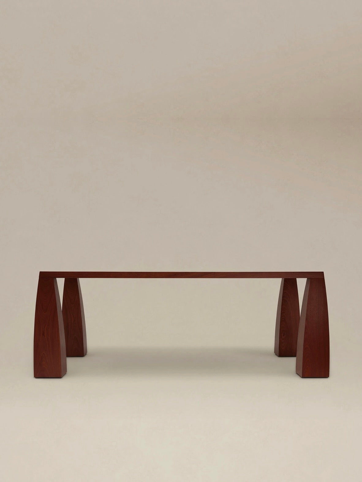 The "Khram" Dining Table by AÈDE Studios is a minimalist wooden piece featuring a flat top supported by sturdy, trapezoidal legs on each side, set against a neutral backdrop.