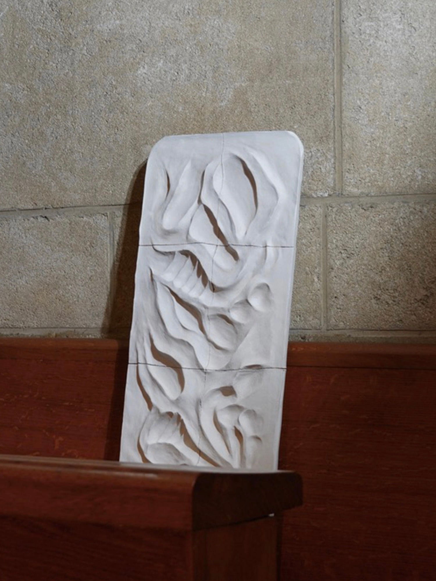 The Death Valley - Wall Sculpture by Franck Scala is a rectangular, abstract white piece with wavy patterns, mounted on wood against stone or concrete. Its smooth texture mimics the natural forms in Death Valley, reminiscent of ceramic bas-reliefs.