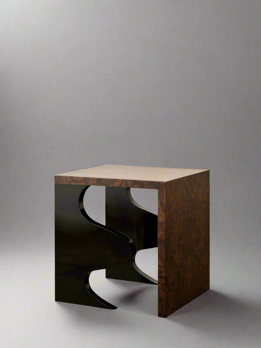 The Harlequin Side Table by Animate Objects features a walnut burl veneer square top with abstract black metal legs. Its glossy lacquered wood finish stands out magnificently against the polished brown and gold floor, while the plain white wall creates a striking backdrop for this luxurious piece of furniture.