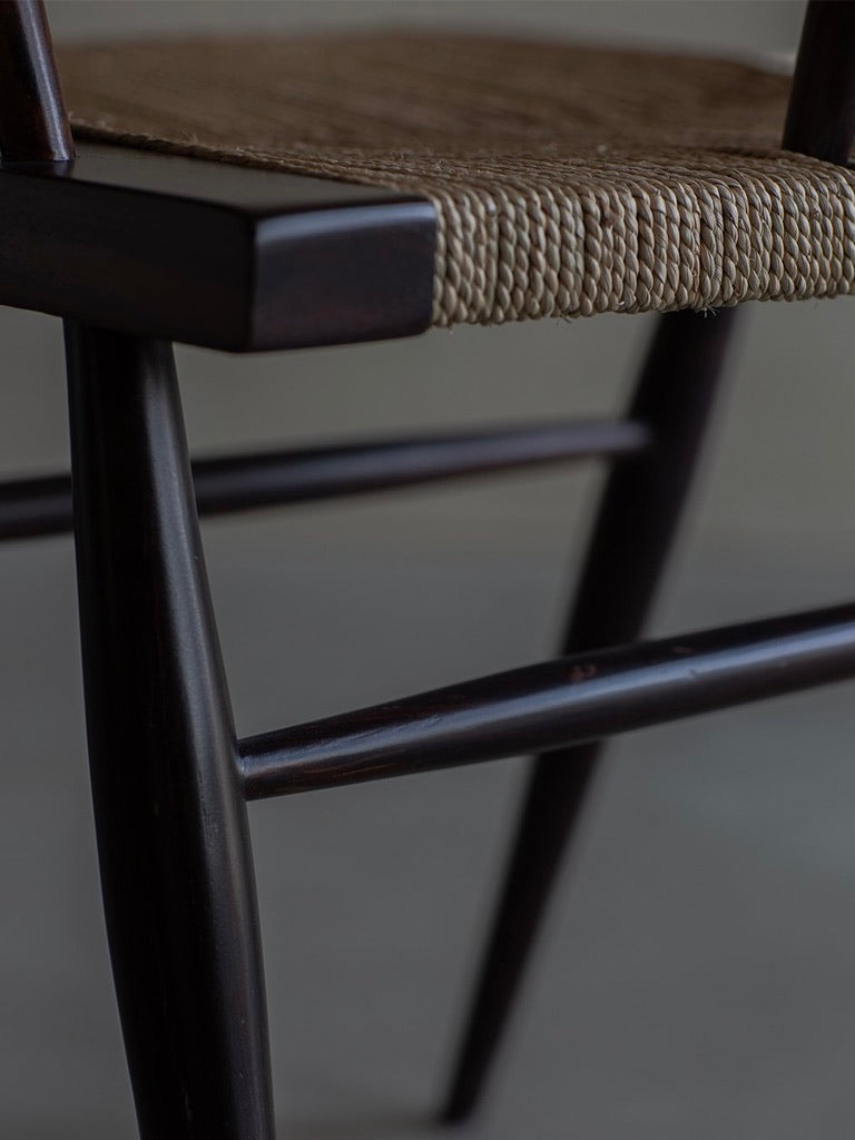 The Manner of Nakashima - Grass Seated Chair by Bicci de' Medici features sleek, glossy dark rosewood legs and a woven seat. The wicker texture is visible, showcasing mid-century allure and contrasting beautifully with the natural material.