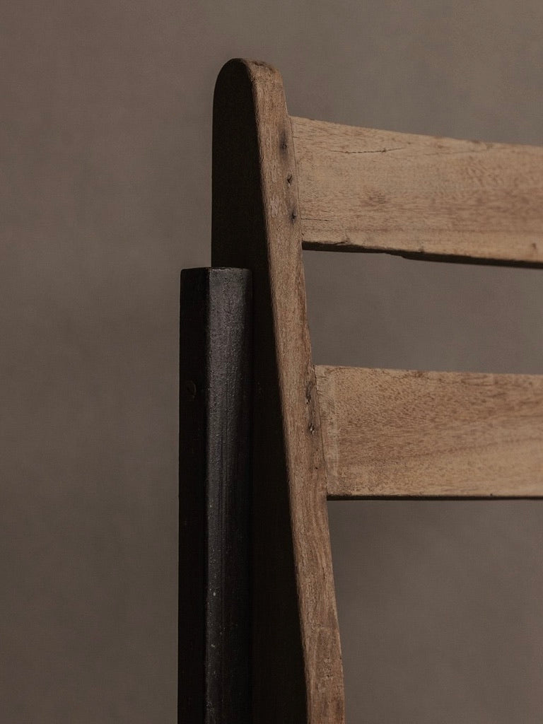 Close-up of an authentic Bicci de' Medici Pierre Jeanneret PJ-SI-65-A chair on a neutral backdrop, focusing on the teak wood slats of the backrest to highlight their texture and natural grain.