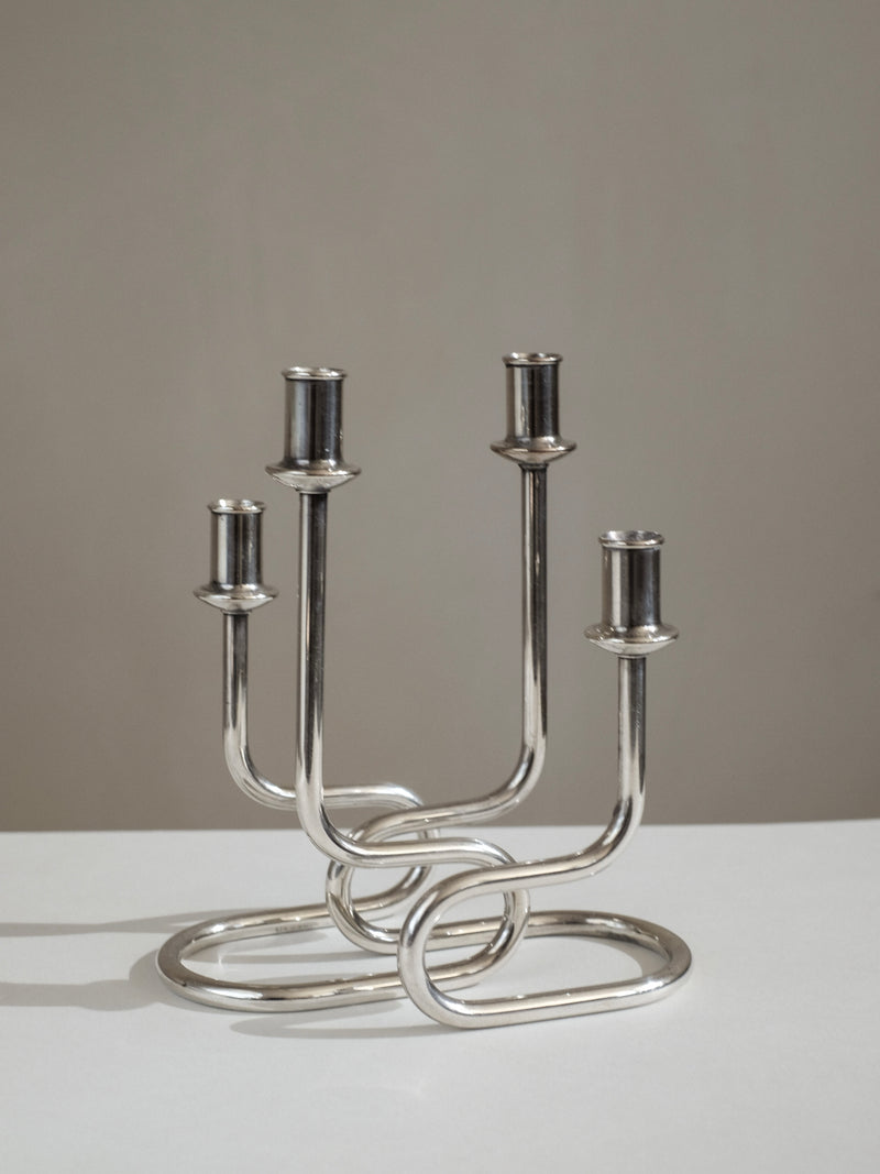 Modern silver metal candelabra with curved interwoven base design