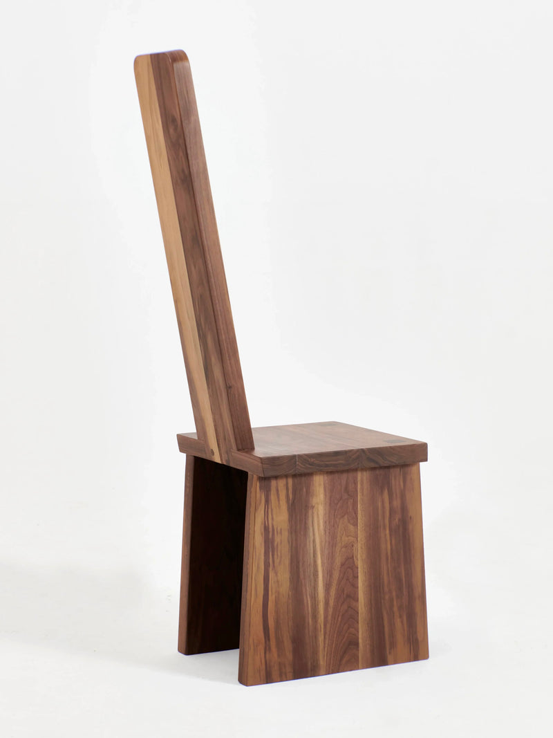 The Portugal Chair No 4 by Project 213A is a modern wooden chair featuring a high backrest and simple, clean lines. Crafted from handcrafted walnut, it boasts a natural wood finish with visible grain patterns and lacks armrests. The minimalist design emphasizes the natural beauty of the wood against a plain white background.