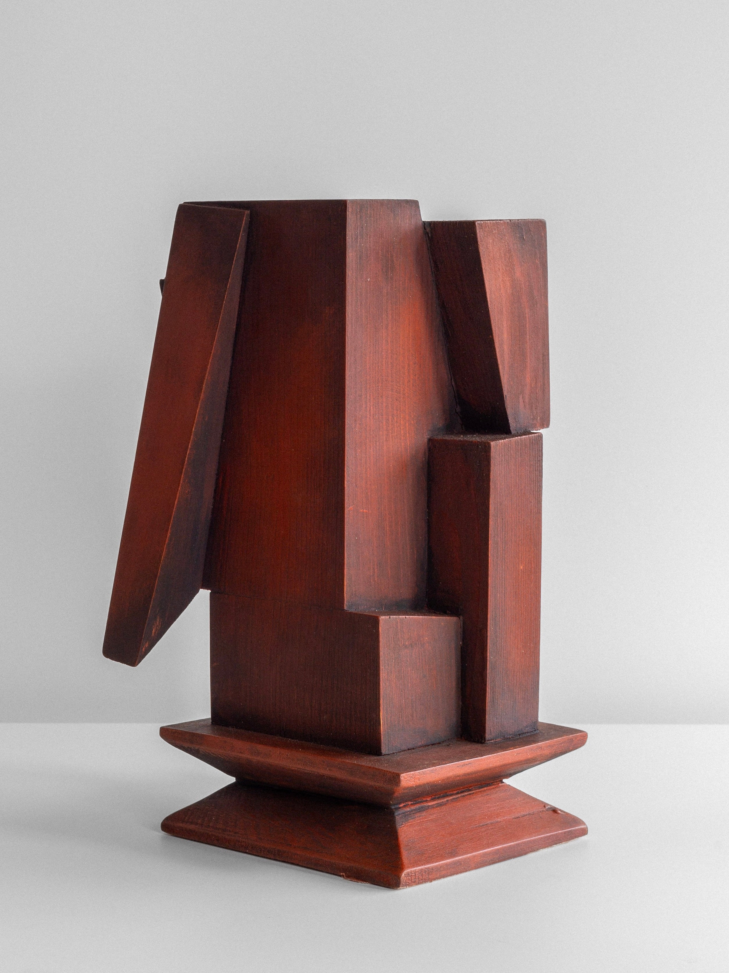 The Vintage Cubist Sculpture by Atelier Boulogne, offered by Spigel, features geometric shapes such as blocks and a flat, angled panel. This figural wood sculpture exhibits a reddish-brown hue and is displayed on a white surface with a plain grey background, capturing elements of cubism in its design.