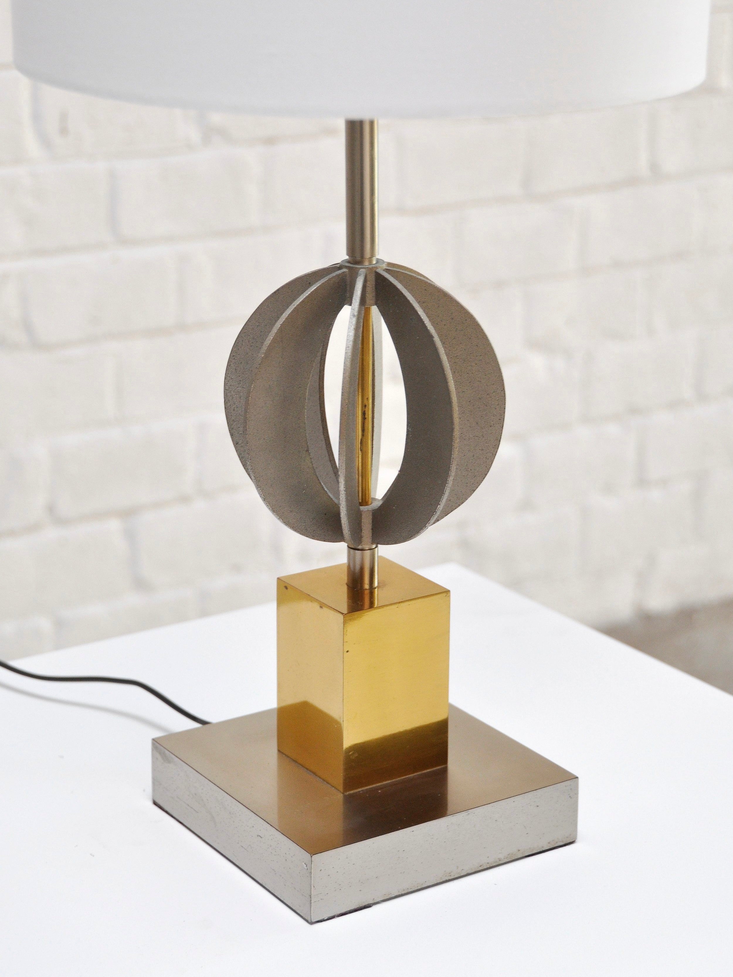 The Pair of Italian Geometric Table Lamps 70's by Introverso feature a modern, sculptural design with a chrome and brass base. Circular silver shapes envelop the stand, providing an abstract geometric look against a white brick background.