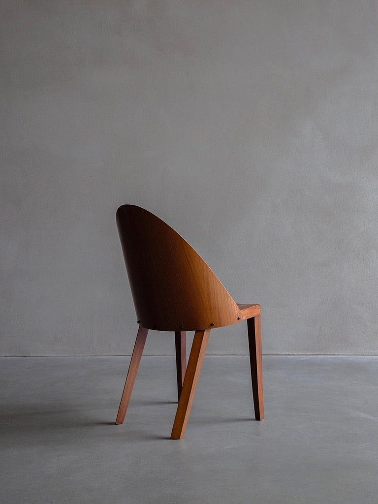 A Philippe Starck - Royalton 44 chair by Bicci de' Medici, with a curved backrest and four legs, rests on a gray concrete floor. Angled left, it embodies the minimalist elegance of iconic designs like the Aleph for Driade, similar to those in places like the Royalton Hotel.