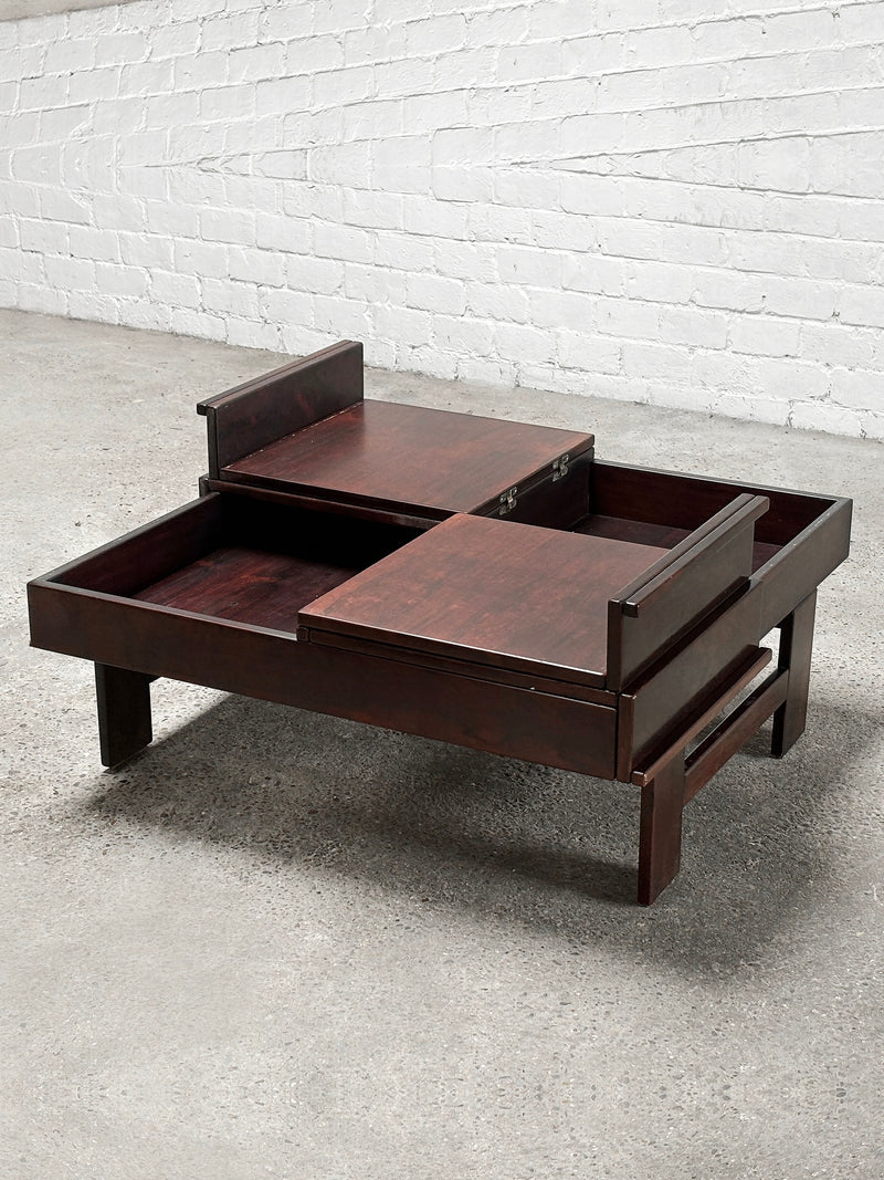 The Square Walnut Coffee Table by Michelucci, Italy 1970's, from Introverso, boasts a modern design with solid wood and two sliding top panels revealing storage. It exudes elegance on a carpeted floor against a white brick wall.