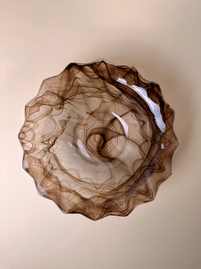 A German Art Deco Cloud Glass Bowl from around 1930 by Dodo Vintage, featuring a pointed rim, is viewed from a top-down perspective. The collectible bowl showcases intricate swirling patterns in shades of brown, creating a marbled look. It sits elegantly on a light beige surface.