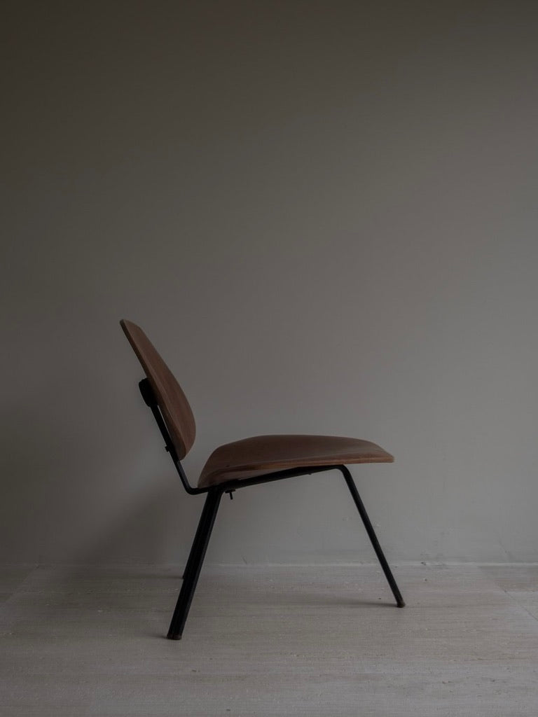 A minimalist side view of the Osvaldo Borsani - P31 by Bicci de' Medici, featuring a sleek brown design with black metal legs against a muted background. Inspired by Italian Mid-Century style, soft lighting creates a calm atmosphere.