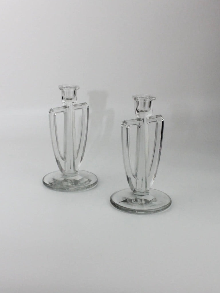 Two Crystal Candle Holders from Boga Avante Shop with an Art Deco design are positioned side by side on a light background. Each candle holder features a cylindrical holder at the top, a geometric pattern on the body, and a round base for stability, offering minimalist and timeless elegance.