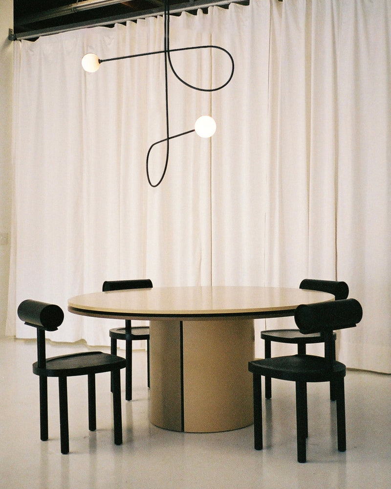 Modern black pendant light with curved sculptural arms over round dining table