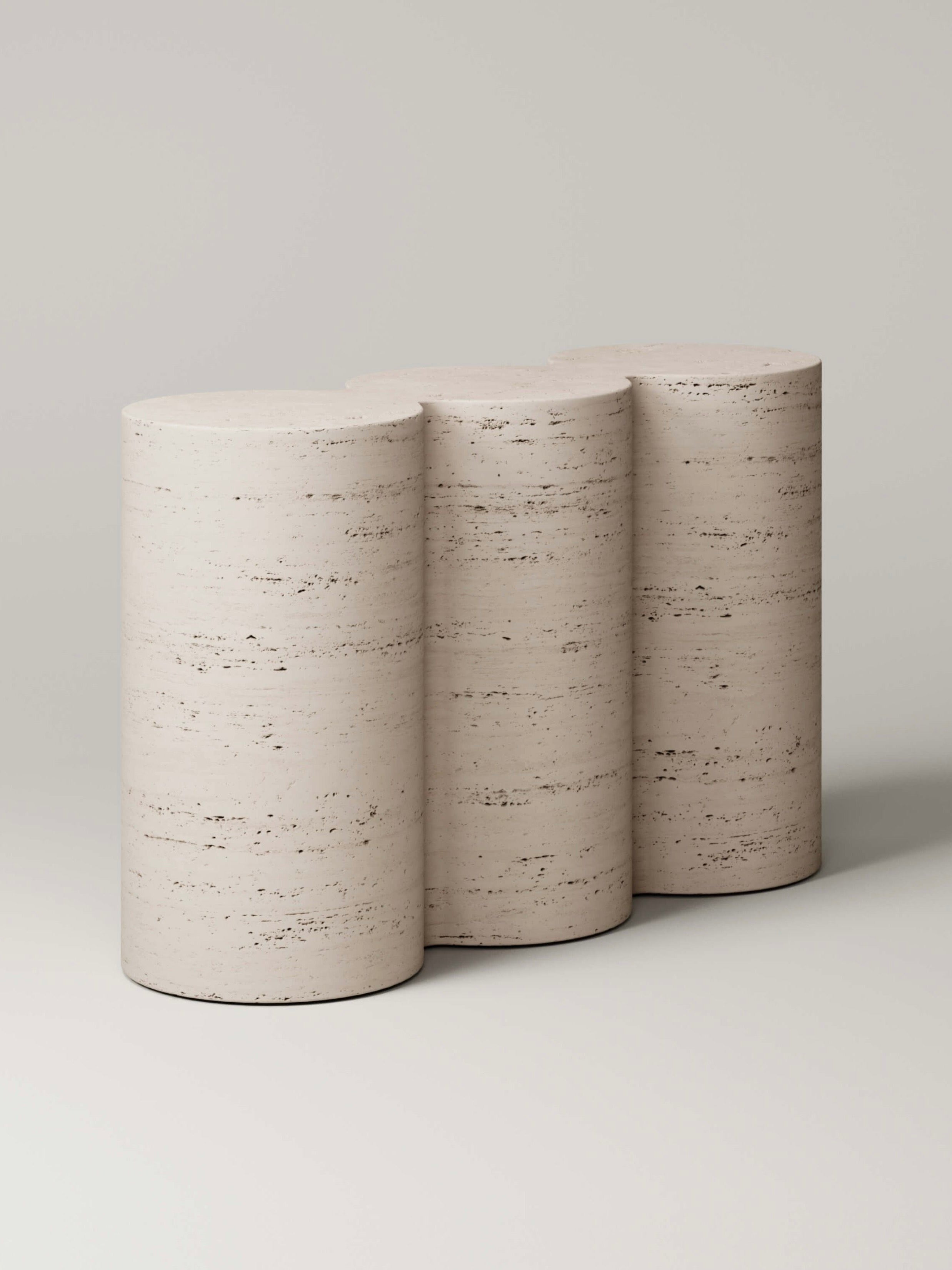 The M_008 Travertine Console by Monolith, designed by Benni Allan, is a beige piece with a textured surface and an undulating silhouette of four cylindrical forms that evoke sculptural triple column geometry for an elegant, wave-like aesthetic.