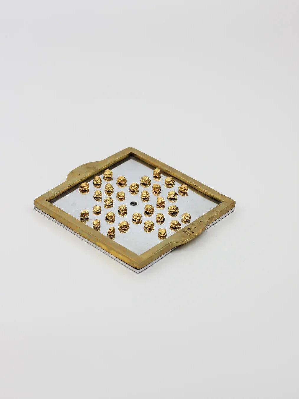 A square frame with handles from the Boga Avante Shop's English Solitaire collection features small, gold, textured objects precisely arranged in a grid pattern. Crafted by David Marshall, this bronze piece is reminiscent of Vintage English solitaire and is showcased elegantly on a simple white background.