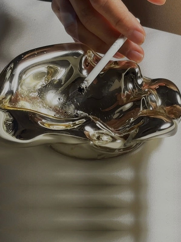 Silver melted ashtray with organic curved form and cigarette