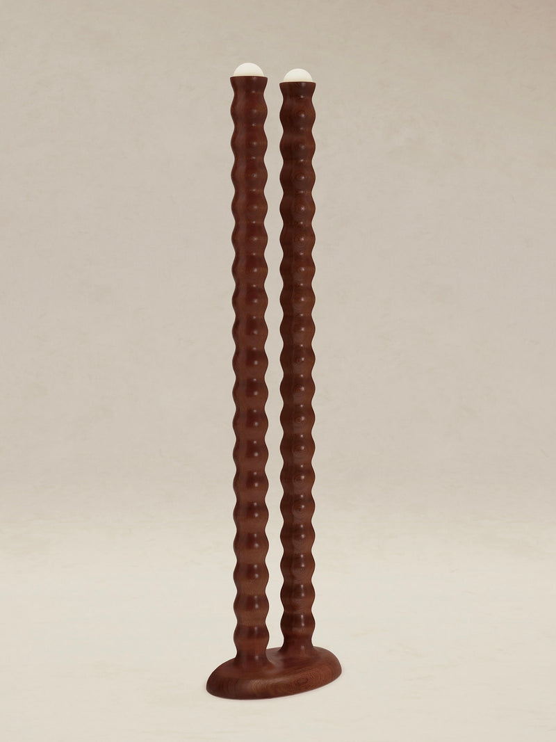 Two tall, wavy wooden "Tougarine" floor lamps from AÈDE Studios stand side by side on a flat base, each topped with a small white knob resembling dual heads, against a plain background.