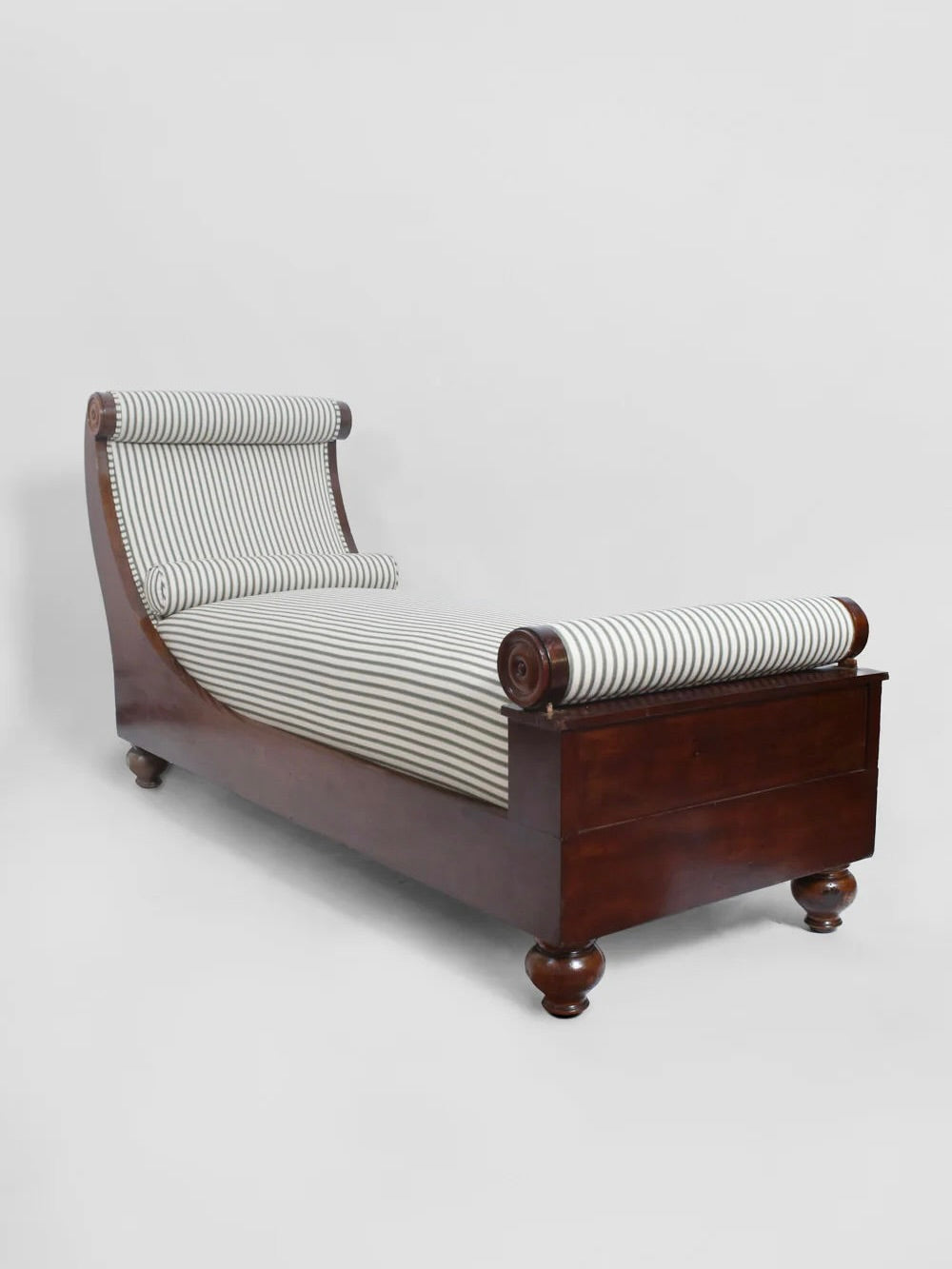 Introducing the Neoclassical Daybed by Barracuda Interiors, inspired by 19th-century France. This exquisite piece features a carved mahogany frame with scroll-like rolled ends at both the head and foot, supported by short, rounded legs. The daybed is elegantly upholstered in black and white striped fabric.