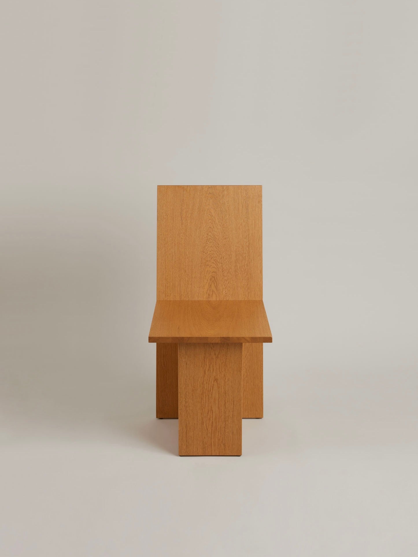 The "La Coupe" Modular Chair by HAUVETTE & MADANI is crafted from brushed oak and features a straight backrest and flat seat. Its minimalist geometric lines are enhanced by a plain, light-colored background.