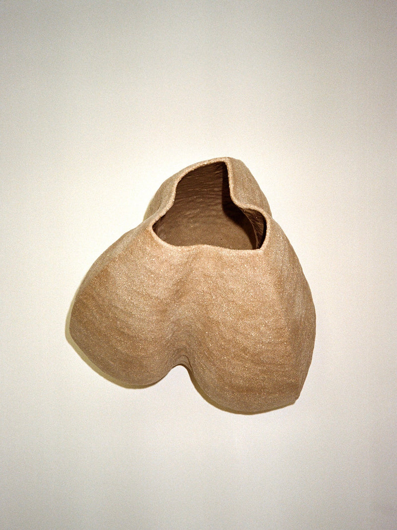Growing Vase n.2 by Aiste Bagdonaite is a beige, abstract hand-built stoneware vase with a textured surface and asymmetrical opening, showcasing organic shapes and artisanal craftsmanship against a light background.