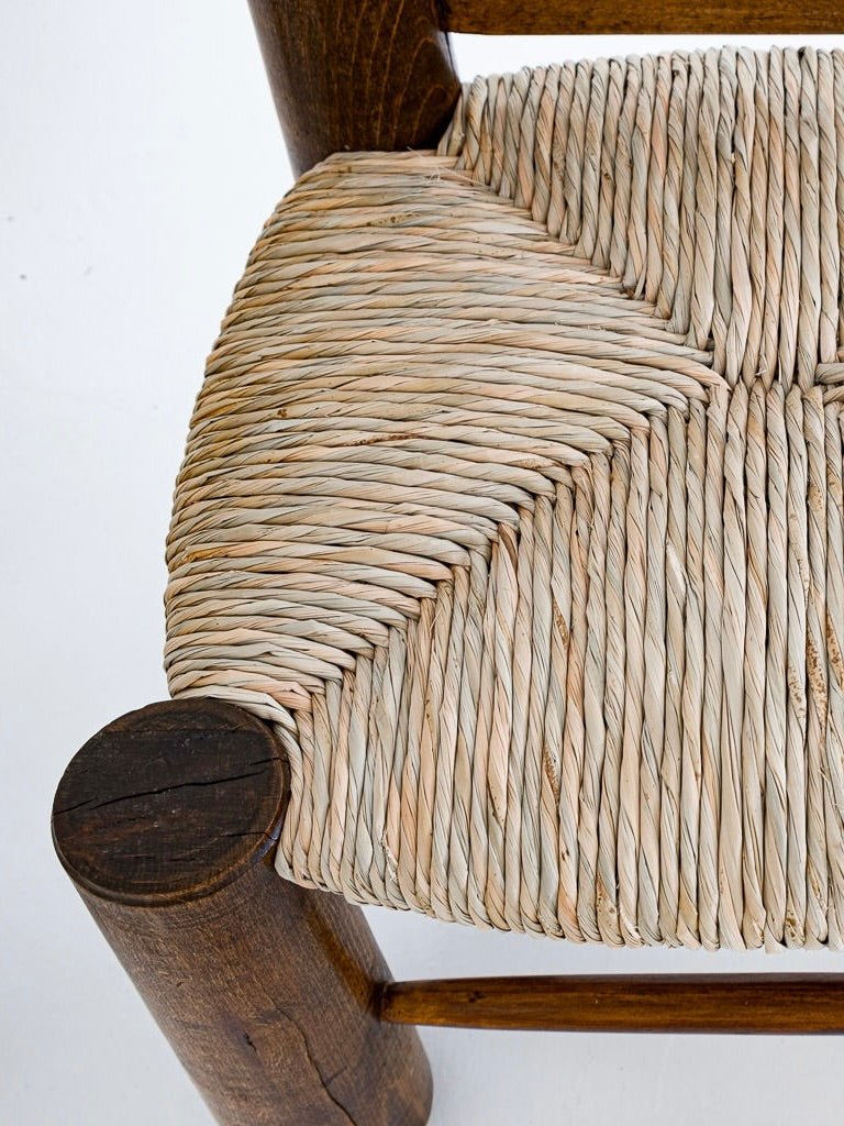 Close-up of a restored 1940s furniture piece by Charles Dudouyt, featuring a woven straw chair seat in diagonal patterns within a solid oak frame. Part of the antibeige Set of 2 Chairs and 1 Table, the rich wood finish beautifully contrasts the light natural seat fibers.