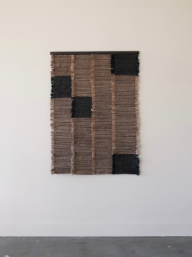 Contemporary woven textile wall sculpture with black geometric patches