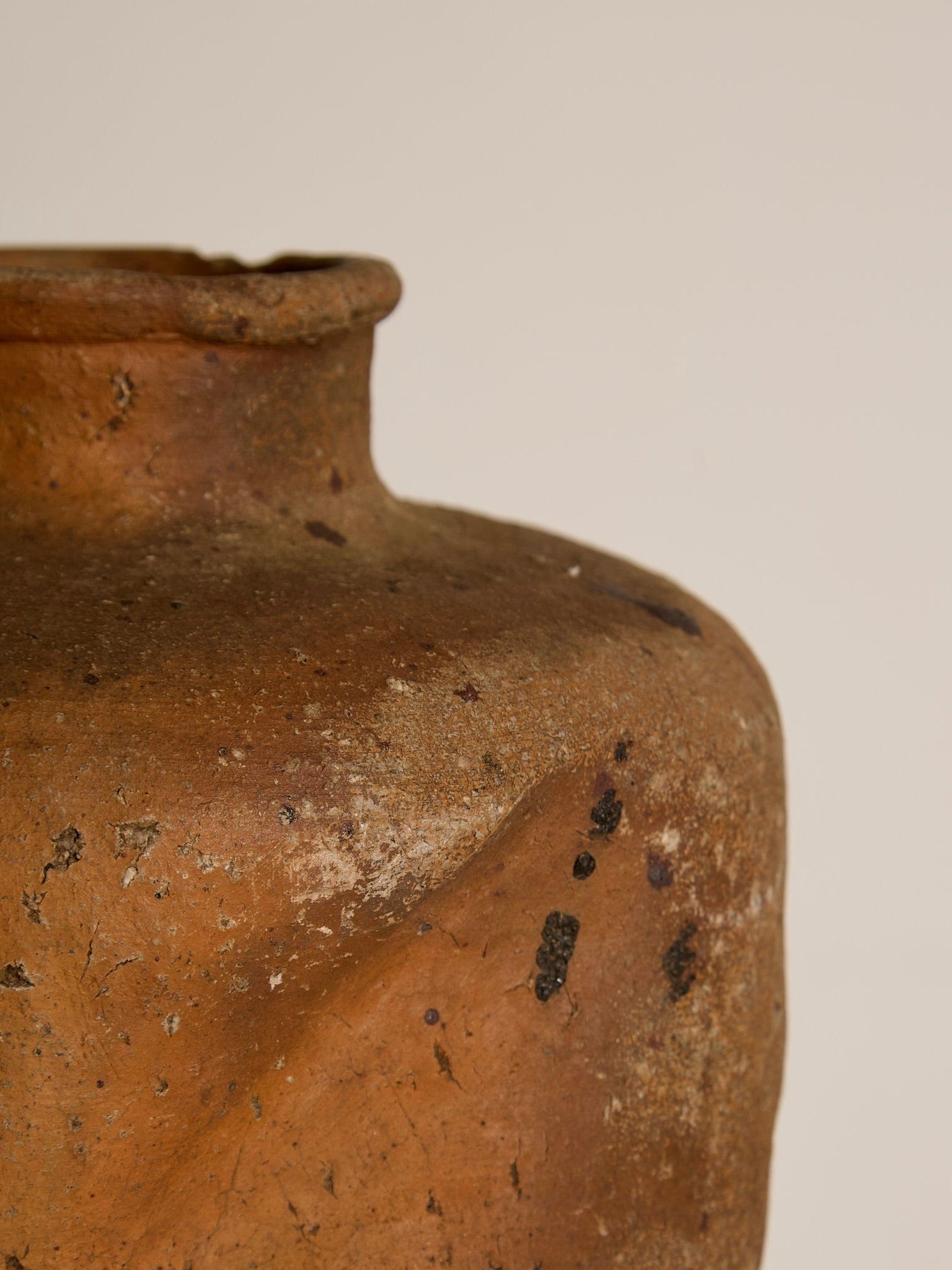 Close-up of a Japanese Stoneware Vessel by Ancien et Jolie, showcasing its rustic, textured surface. Earthy brown tones with dark speckle glaze and natural imperfections highlight its aged look against a soft, neutral background evoking Kasam Japan's timeless elegance.