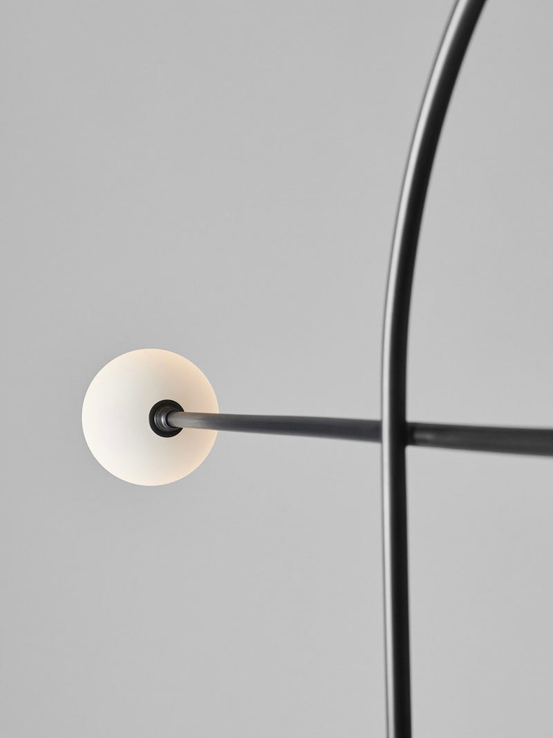 Black metal floor lamp with illuminated white disc detail close-up