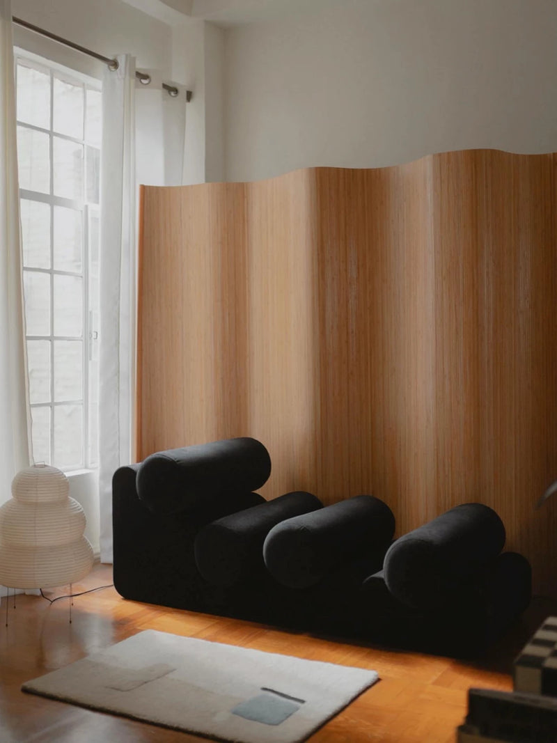 Black velvet curved lounge chair with plywood screen backdrop