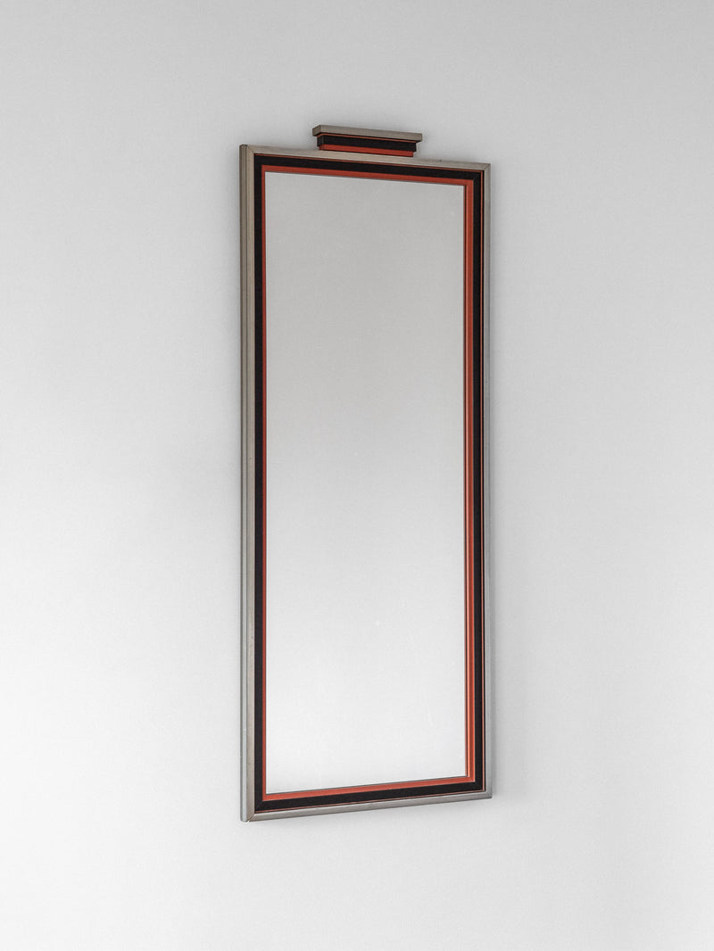 The Spigel Art Deco Mirror from 1930s Sweden, featuring a decorative frame with a subtle red accent, is mounted vertically on a plain white wall.