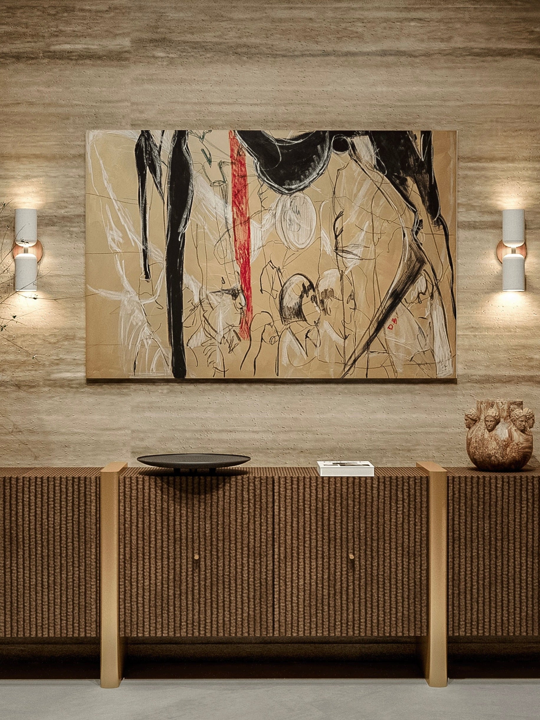 A textured beige wall displays "Isolated Calm," an abstract painting by Dovile Bernotaite, rendered in muted tones of black, red, and white. Below it is a long console table with a woven front, holding a black tray, a white book, and a decorative clay sculpture. Twin wall sconces with double lights flank the solitary presence of this artful setup.