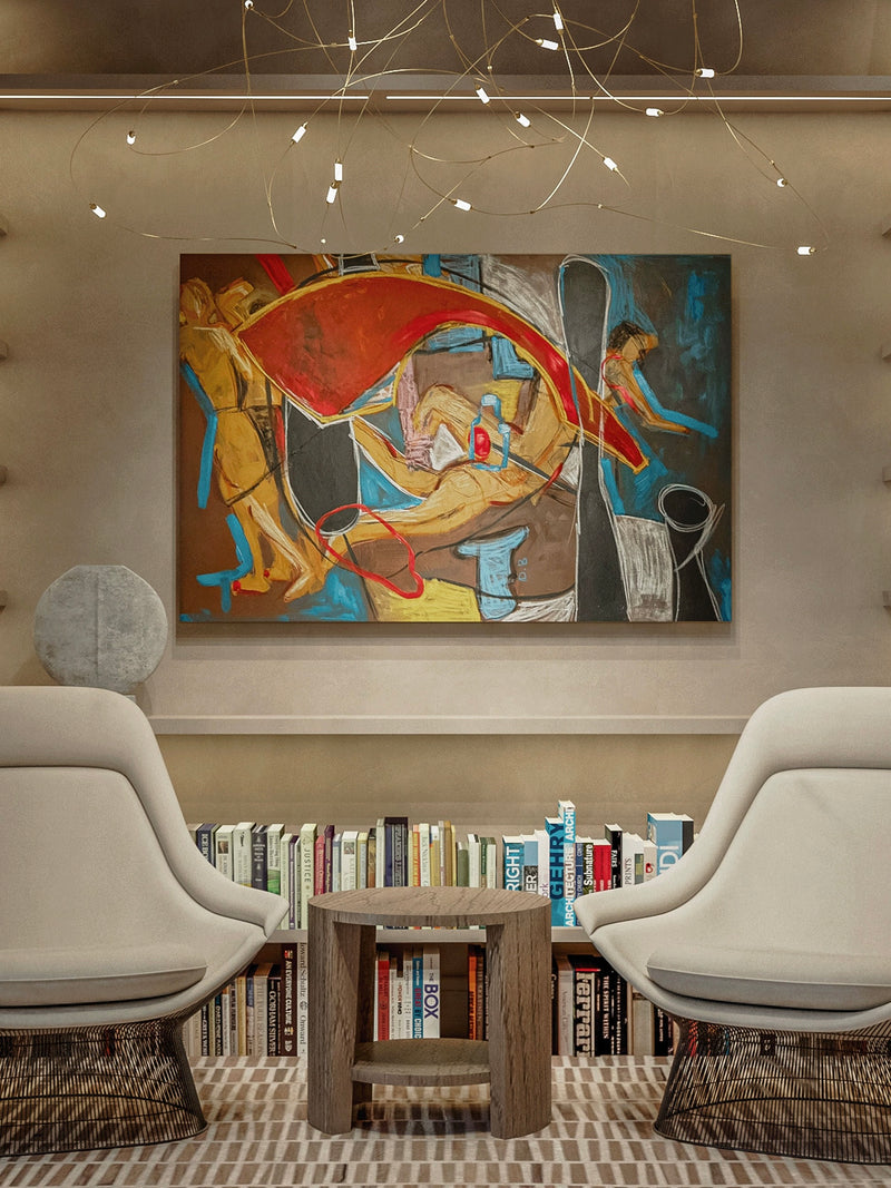 A cozy reading nook features two modern white chairs with wicker bases facing a small wooden table. Behind them is a bookshelf filled with books and above, "Daydreaming," an exquisite piece by Dovile Bernotaite, showcasing bold colors and surreal forms created in acrylic, oil pastel, and charcoal on canvas. The space is softly lit by decorative ceiling lights.