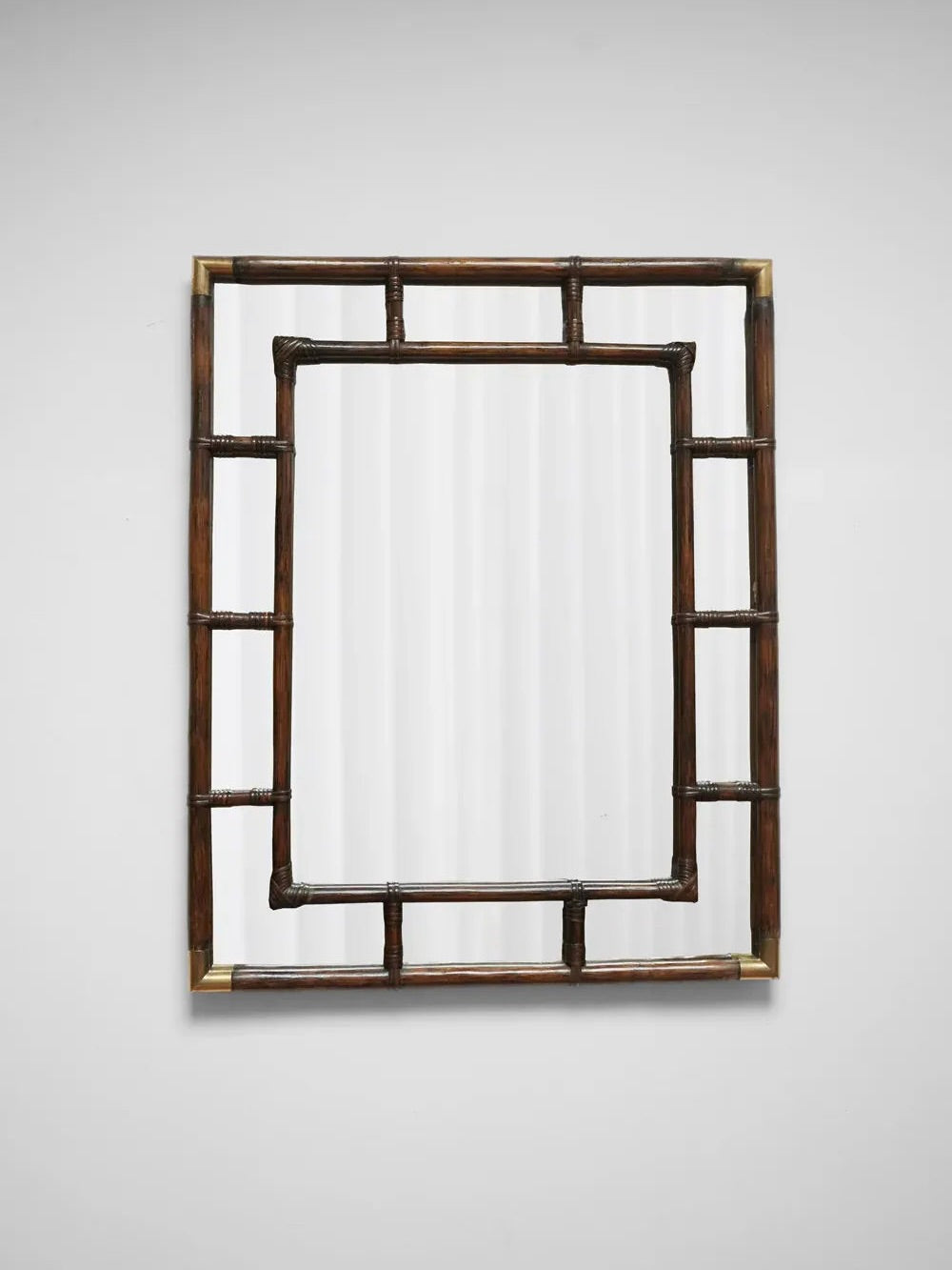 A rectangular Brown Rattan and Brass Mirror from the 1970s by Barracuda Interiors features a decorative frame with a geometric pattern of intersecting bars, enhanced by tubular brass accents against a simple white background.