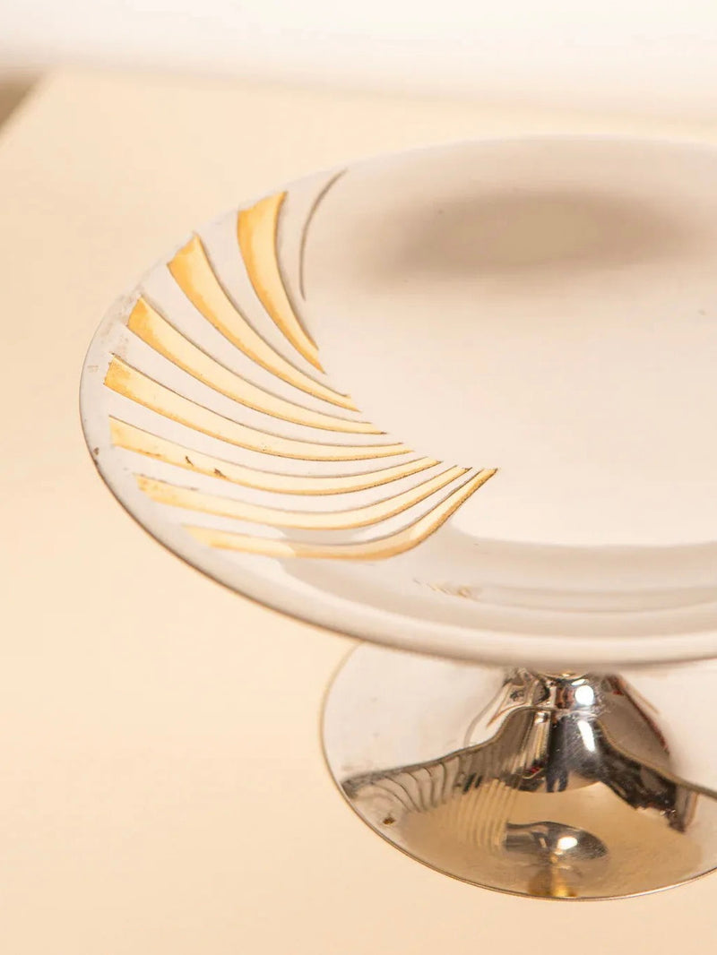 The 60's Fruit Coupe in Metal and Brass by Treaptyque adorns a cream-colored surface, showcasing exquisite craftsmanship. Its design, inspired by a 60's fruit basket, beautifully combines modern minimalism with retro charm.
