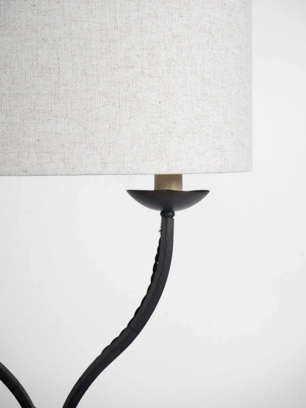 Close-up of the Barracuda Interiors Iron Floor Lamp, 1960s, featuring a textured off-white fabric lampshade. This lamp, inspired by 1960s France, showcases a minimalist black metal stand with an oval base and a curved symmetrical design against a plain white background.