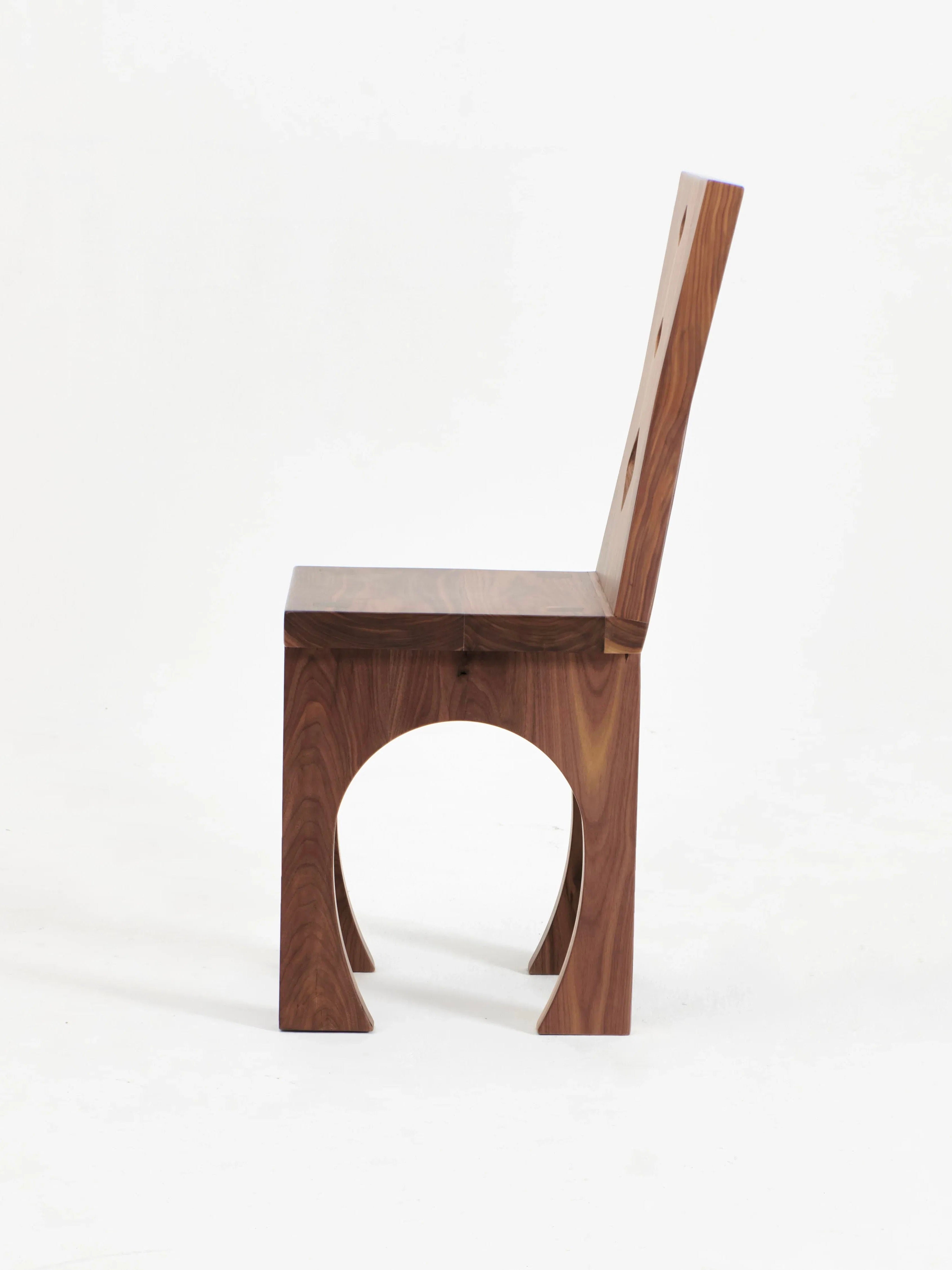 Here's the revised sentence using the given product data:

The Portugal Chair No 2 by Project 213A is a distinctive wooden chair with a minimalist design, crafted from solid walnut. It features a straight backrest and seat, both with a smooth finish. The legs form an arch-shaped base that adds an artistic element to the design. The chair is set against a plain white background.