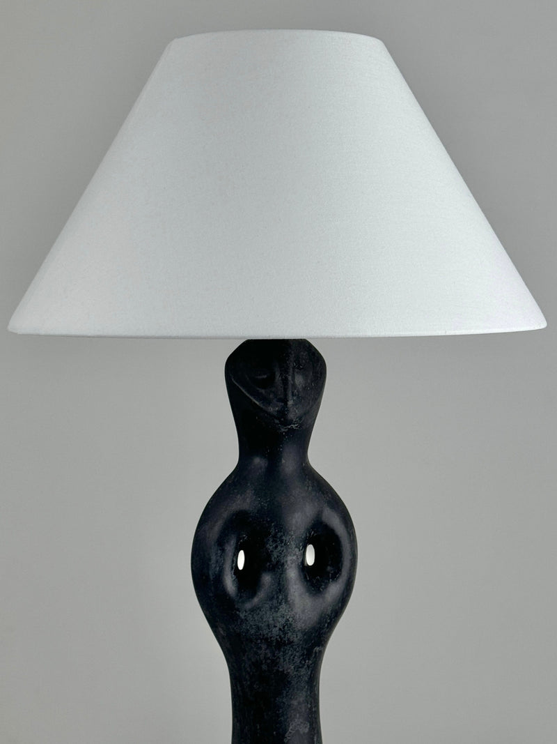 The Figuresdesign Black Marble Anthropomorphic Table Lamp showcases an abstract human figure base in black marble with a large white conical lampshade, capturing mid-century 1950s elegance against a plain gray background.