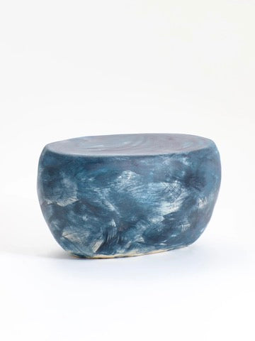 A smooth, rounded ceramic coffee table by Project 213A showcases a blue and white marbled pattern, resembling a polished stool or low seat. Set against a plain white background, this hand-sculpted piece features custom glaze detailing for an exquisite allure.