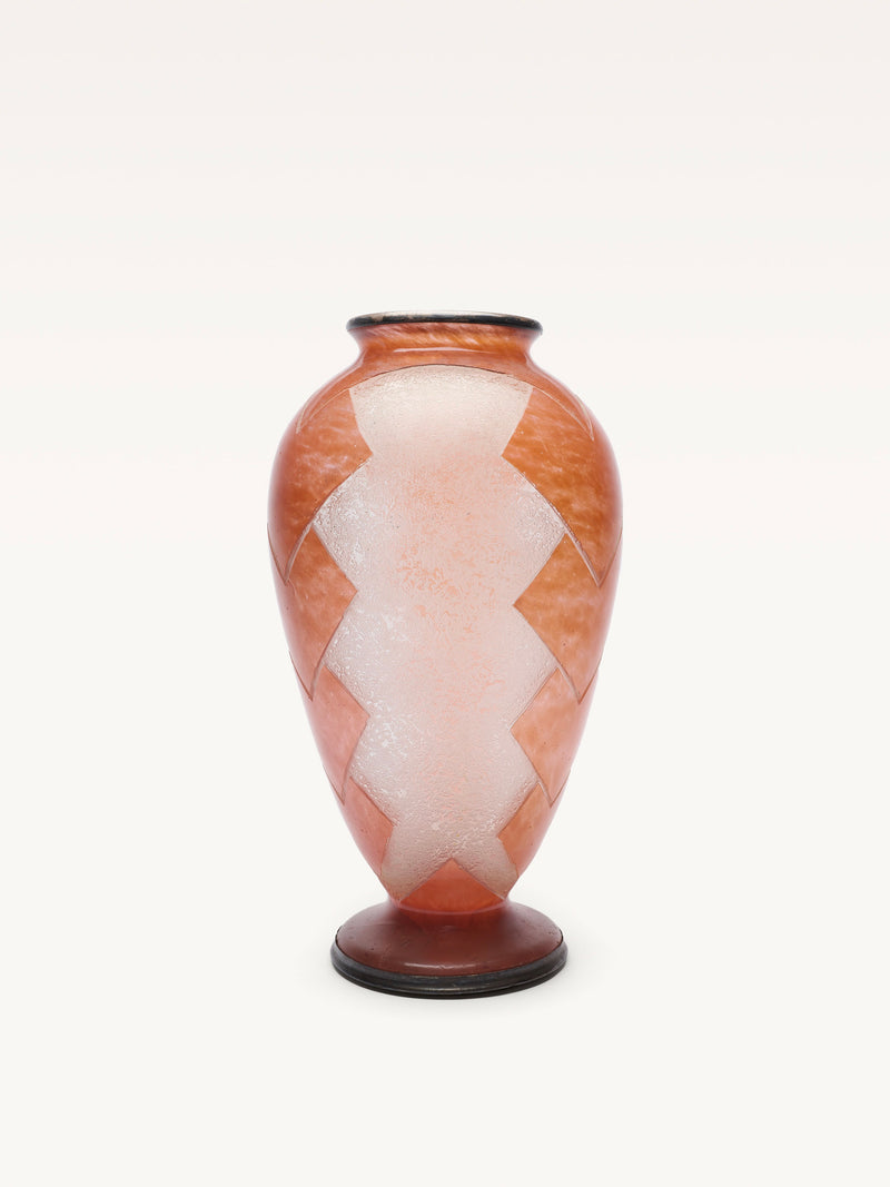 The Galerie MLS Glass Baluster Object is a tall, reddish-orange Art Deco vase with a wide body, narrow neck, zigzag white sandblasted geometric patterns, and a round dark base, reflecting a 1930s style against a plain white background.