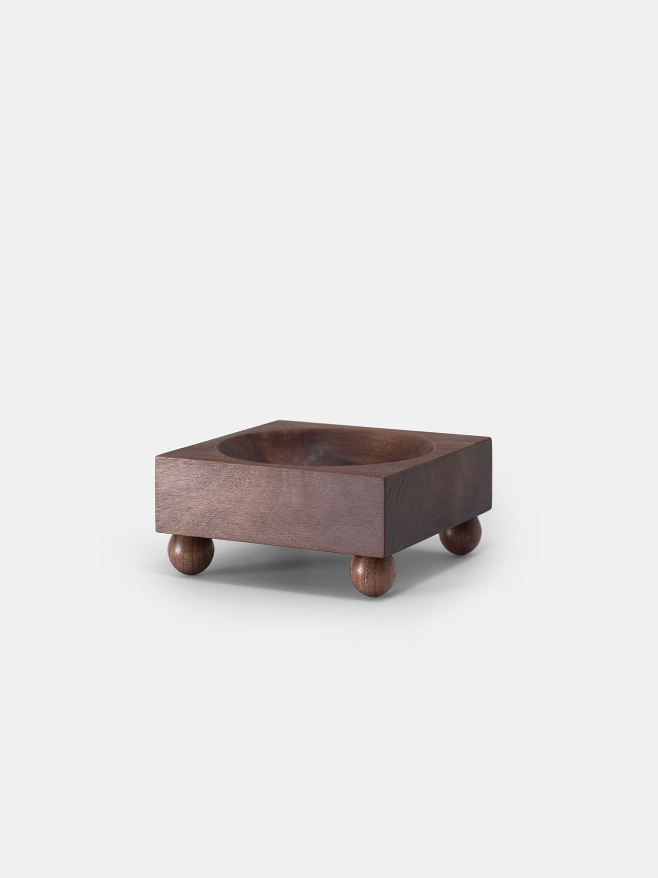 Part of Studio Vraco's TSDXSV Collection, Tray 01 Walnut features smooth edges and a deep interior supported by four small round feet. The rich, dark walnut finish accentuates its natural grain against a plain white backdrop, emphasizing the modern design's simplicity and elegance.