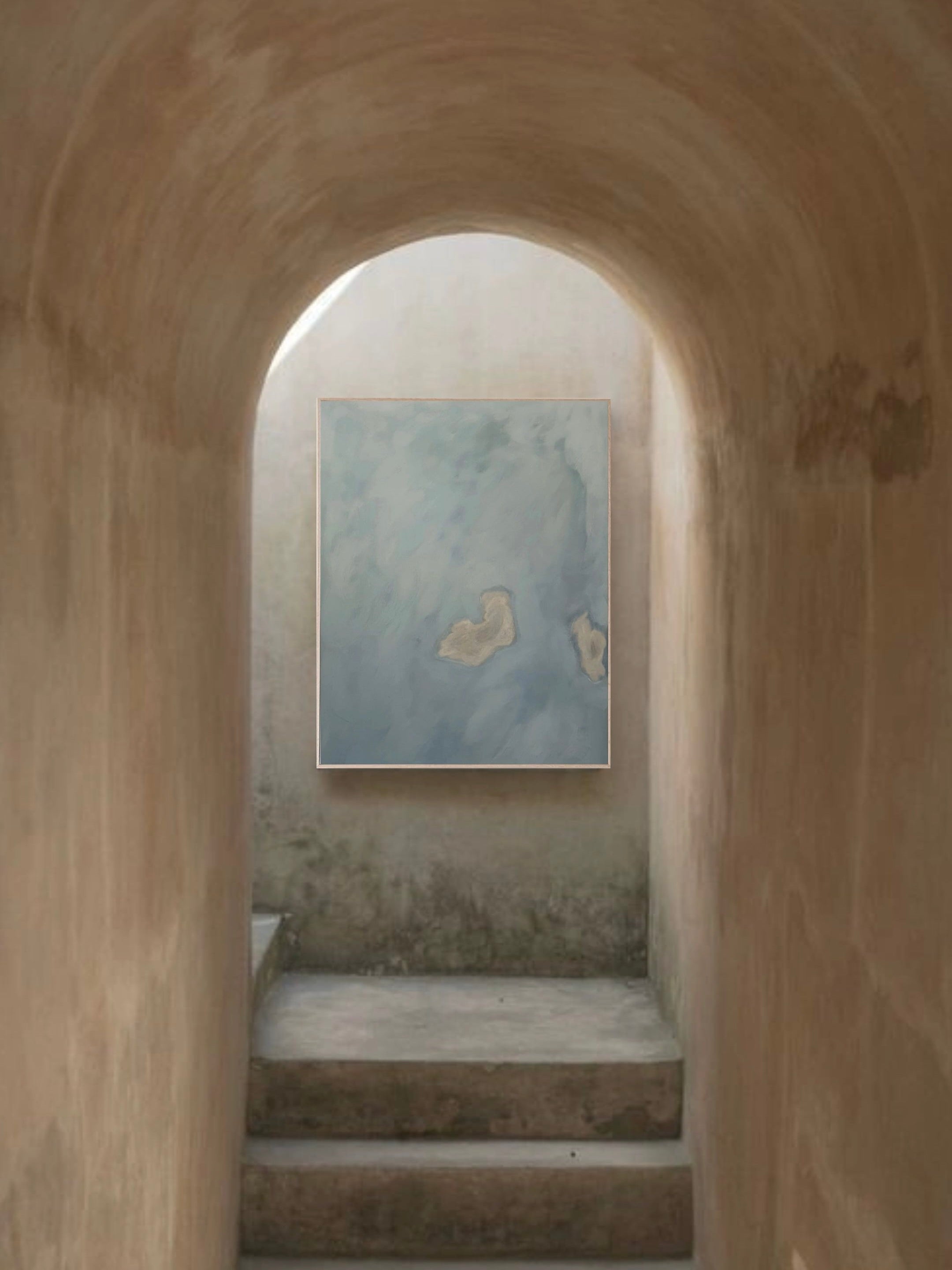 A hallway with curved light brown walls leads to a staircase. At the top, "I think of you in colors, that do not exist," a square abstract painting by Yeliza Gevorgyan in soft blue and beige, crafted with natural pigments to explore subtle color relationships, is mounted on the wall.