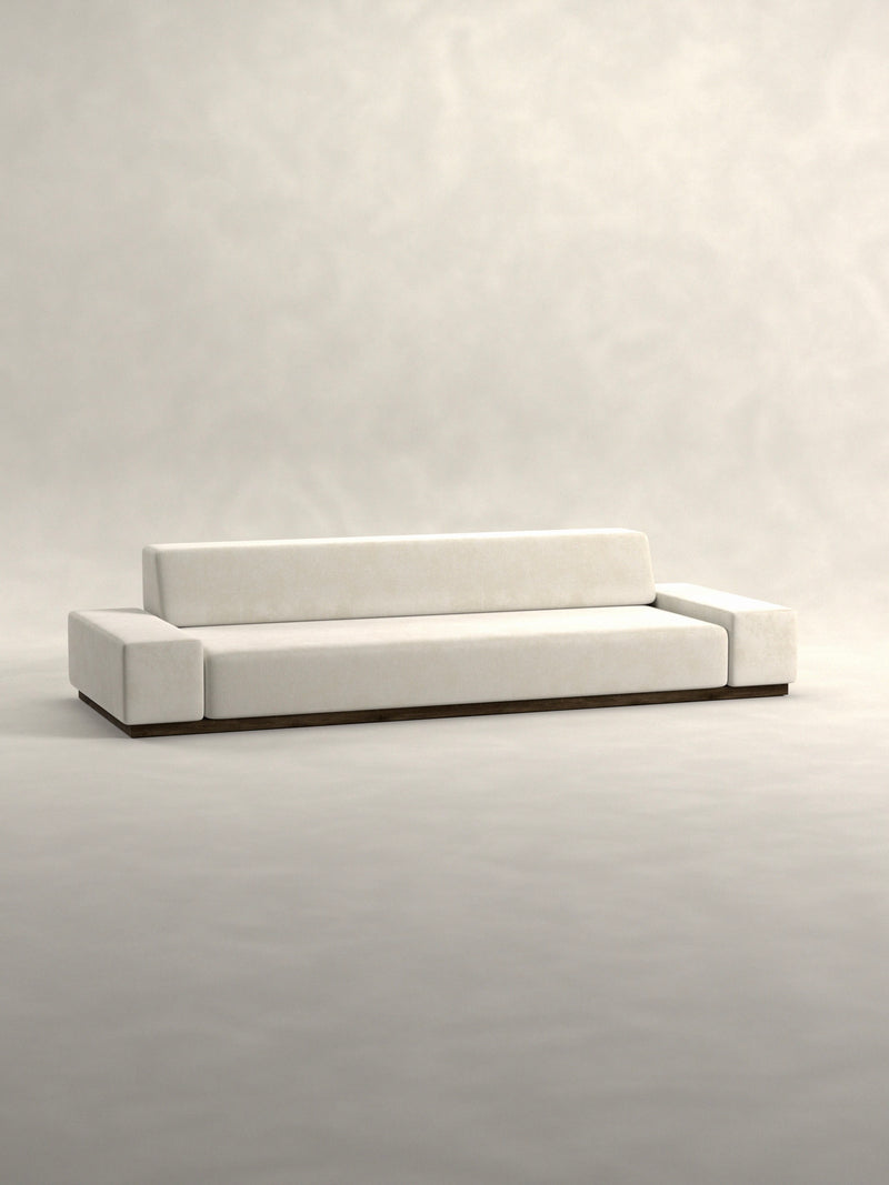 Siete Studio's 'Nube' Sofa is a minimalist masterpiece with clean lines, featuring light gray upholstery, a low rectangular backrest, and wide armrests. Its sleek design sits on a solid walnut base inspired by 70s Italian aesthetics.