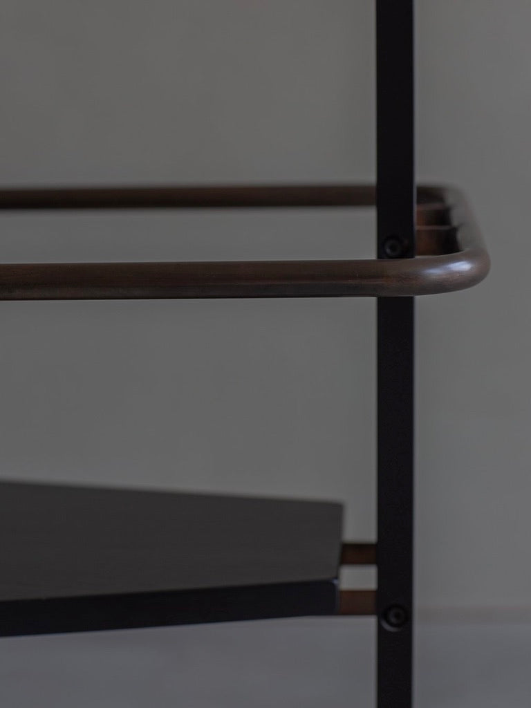 Close-up of Jonas Bohlin's CONCRETE bench by Bicci de' Medici, featuring a minimalist dark brown metallic frame and black seating. The design, akin to a concrete chair, showcases straight lines and a modern aesthetic against a plain background.