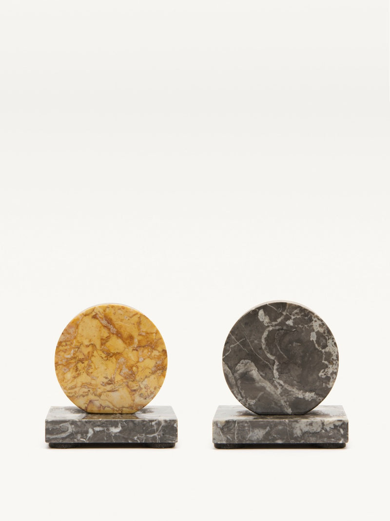 The Pair of Art Deco Marble Bookends by Galerie MLS features a yellow marble bookend with brown patterns and a dark gray marble bookend with lighter veining, both on square bases that capture the elegance of the French 1930s.
