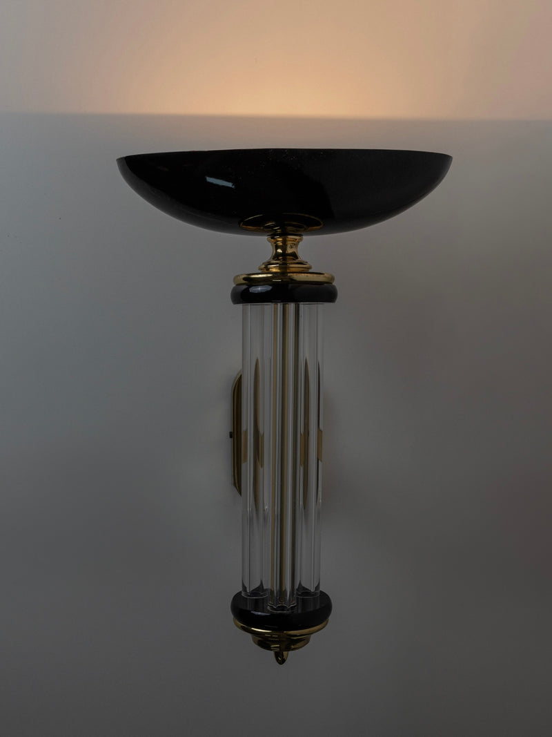The Bottega Jacobs Wall Light - Italy 1980s showcases a black round shade with a cylindrical glass center and gold accents, epitomizing Hollywood Regency style. This vintage light casts an elegant, soft glow for a sophisticated wall ambiance.