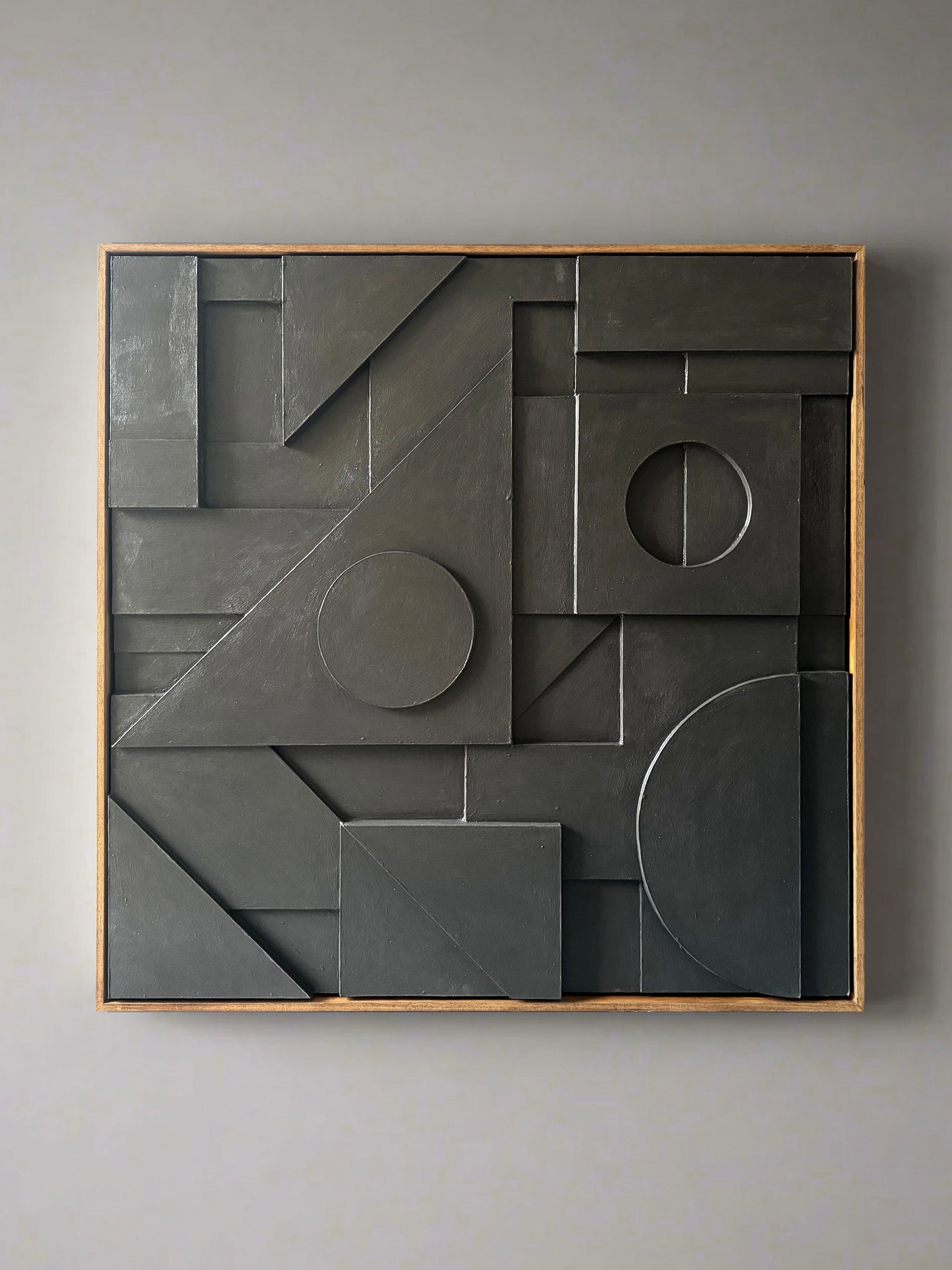 The Composition147 Sculpture by Sean Thornhill is a wooden-framed, Bauhaus-inspired abstract artwork featuring a layered 3D effect with geometric shapes like circles, rectangles, and triangles in dark gray shades.