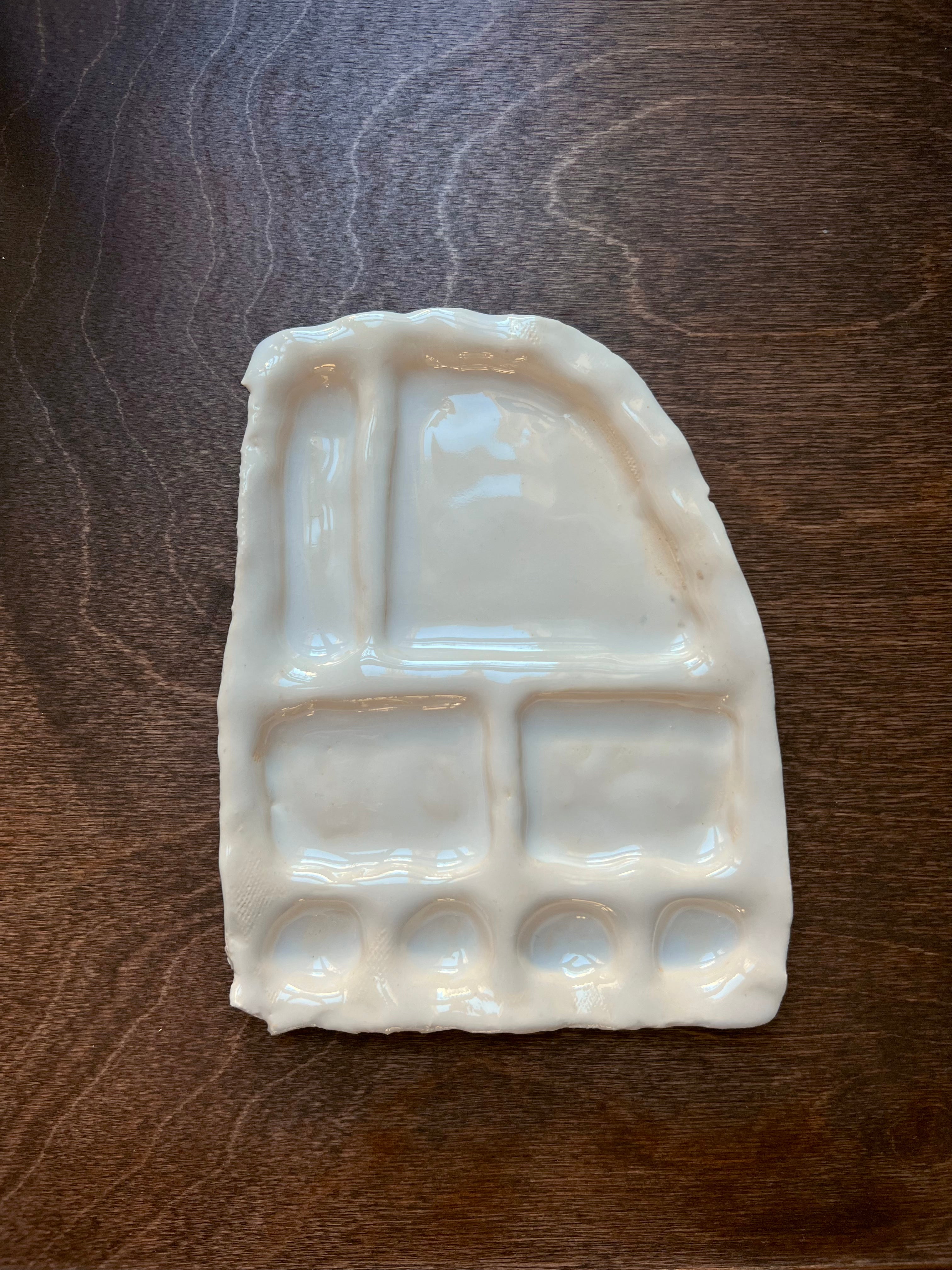 A handcrafted ceramic Somthings Snack Plate, shaped like a cartoonish car, with sections and indentations, placed on a dark wood surface.