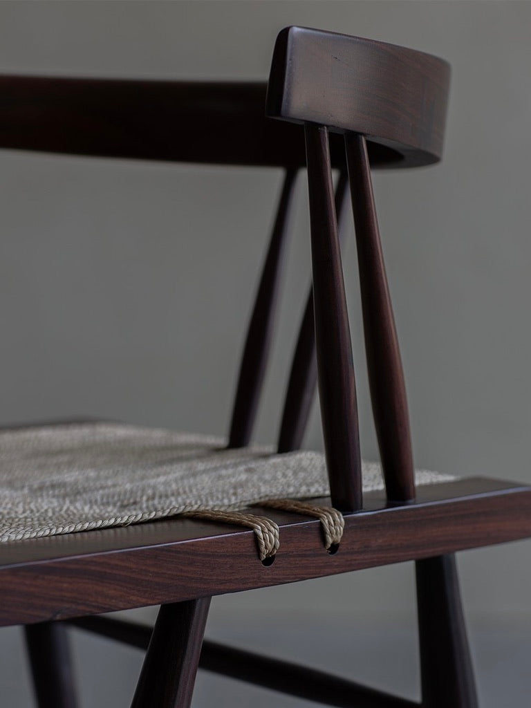 Close-up of the Manner of Nakashima - Grass Seated Chair by Bicci de' Medici, featuring a dark rosewood frame and a woven seat. This chair exudes mid-century allure through its minimalist design, straight lines, and smooth finish against a plain background.