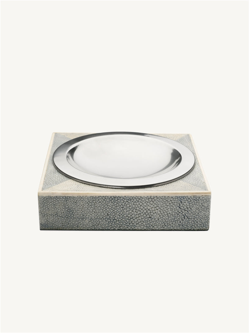 The Shagreen Ashtray by Galerie MLS is a square, gray piece with a textured finish and a round, shiny silver dish set into the top, shown on a plain white background.