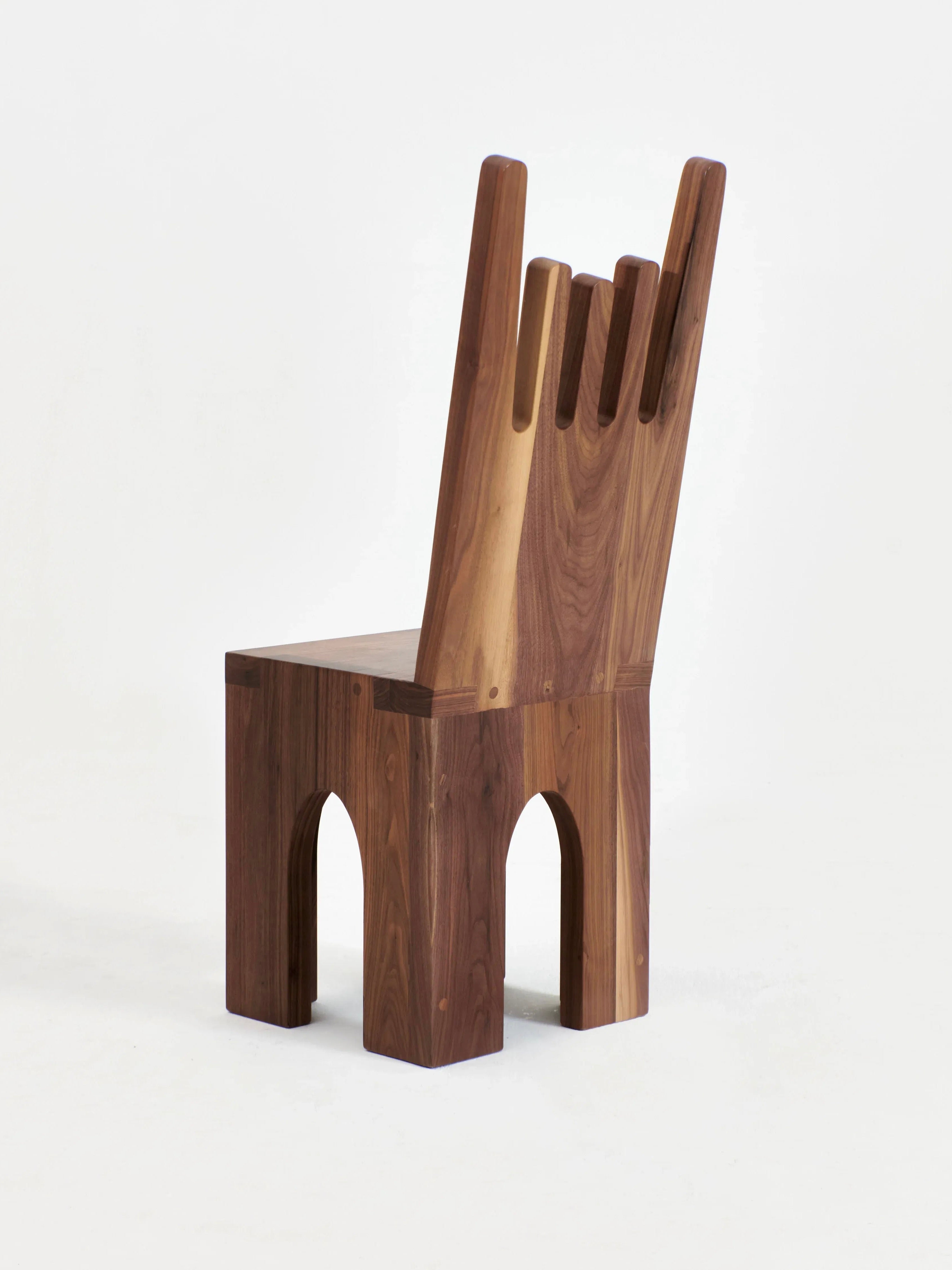 The Portugal Chair No 5 by Project 213A is a wooden chair crafted from solid walnut, featuring a distinctive graphic-shaped backrest with four differently sized rectangular cutouts. Its solid rectangular legs have arch-shaped spaces at the bottom, beautifully showcasing the visible wood grain and highlighting its natural texture and color variations.